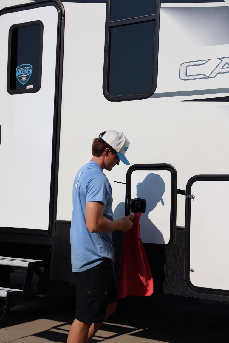 Skylo technician hand waxing an RV panel with a red towel